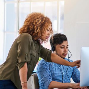 Two colleagues collaborating on a project at a computer in a bright office.