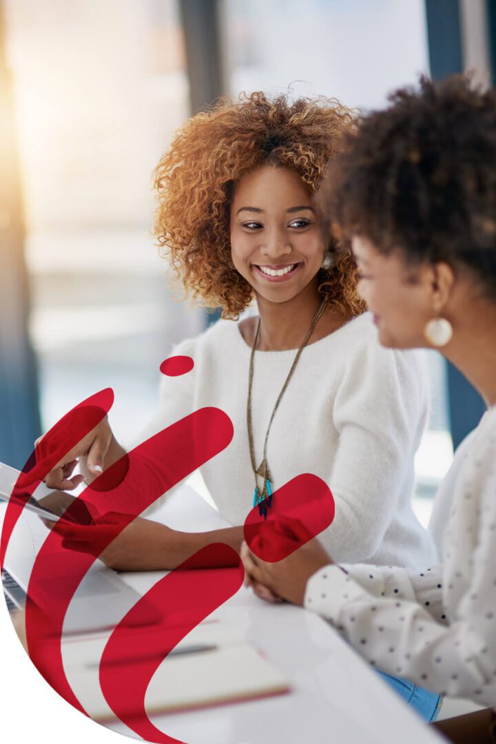 Two women sharing a joyful moment with red heart shapes.