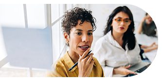 Thoughtful woman holding a pen, engaged in discussion.