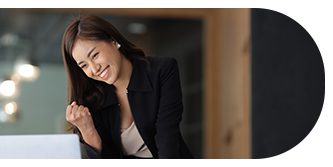 Smiling woman in black blazer leaning on a surface indoors.