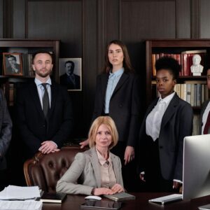 A professional business team posing in an office with a seated leader.
