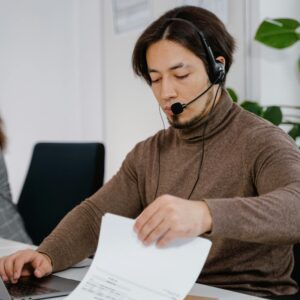 Woman working in a call center, reviewing documents with headset on.