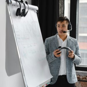 Man in a blazer giving a presentation with a headset and coffee mug.