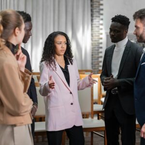 A woman leads a discussion with a diverse group in a professional setting.