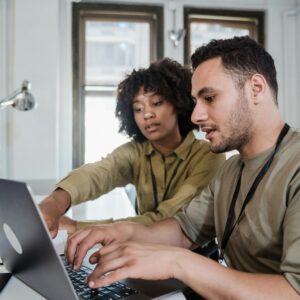 Two colleagues collaborating on a laptop in an office.