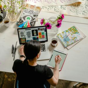 Person working on art and design projects at a cluttered desk.