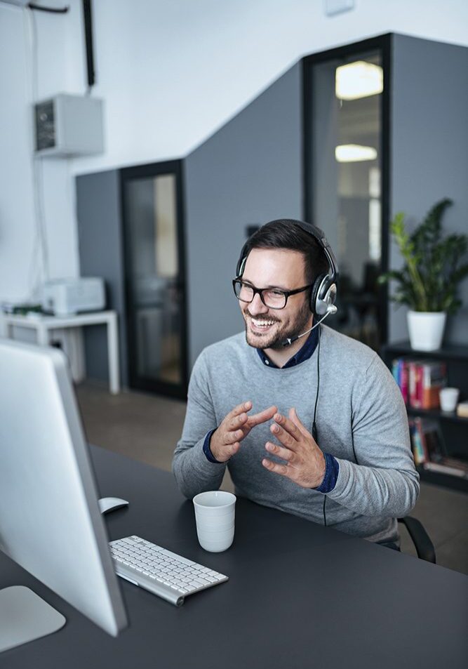 Man video conferencing with headset at desk.