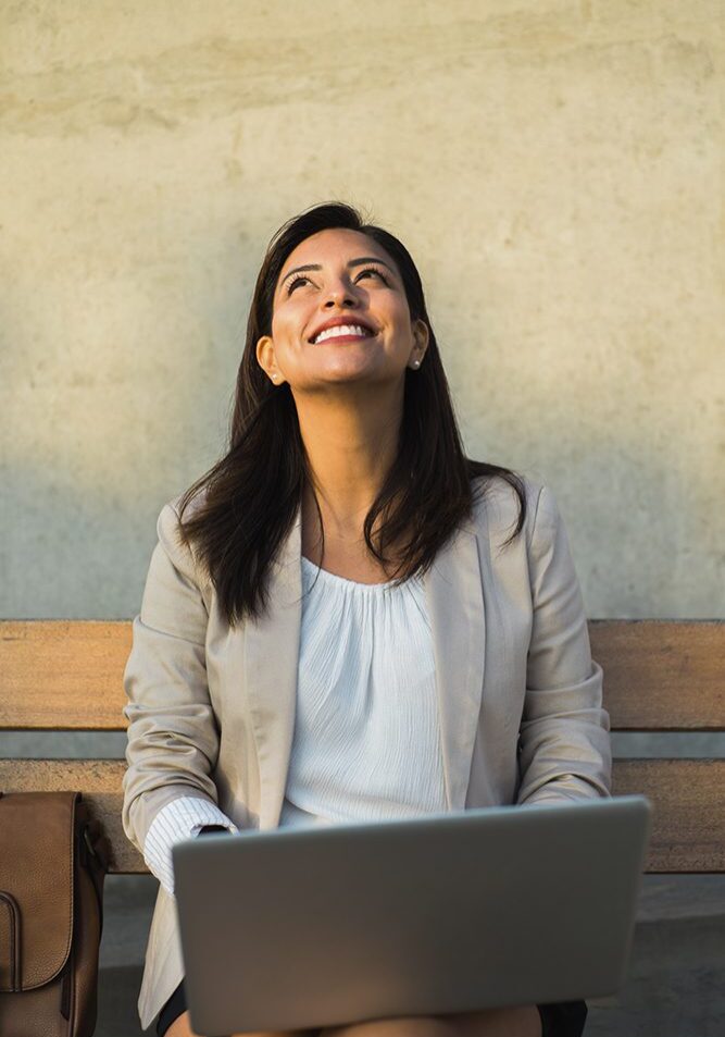Woman smiling with laptop, looking upwards.
