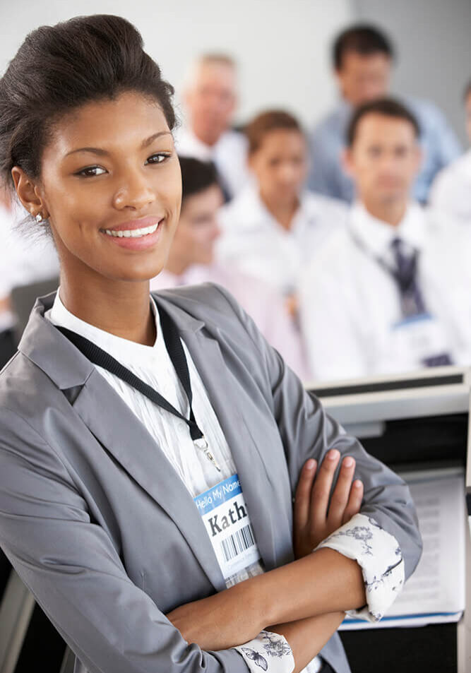 Confident businesswoman smiling with colleagues in the background.