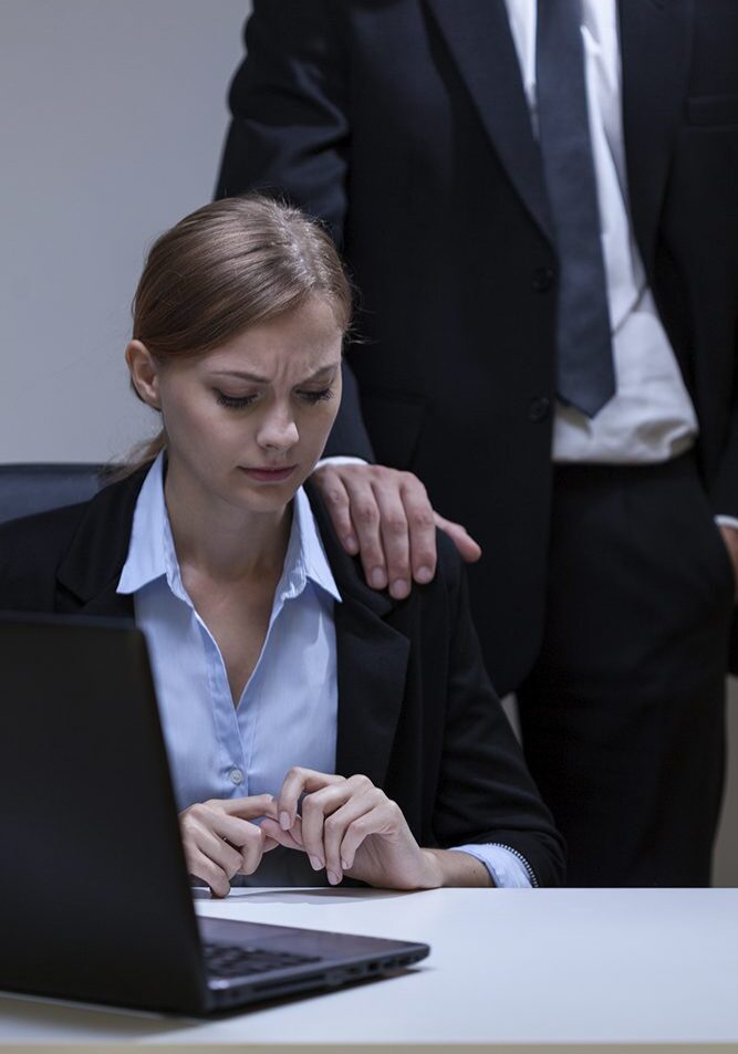 Woman at desk with man's hand on shoulder.