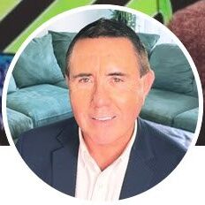 Professional man posing indoors with a sofa in the background.