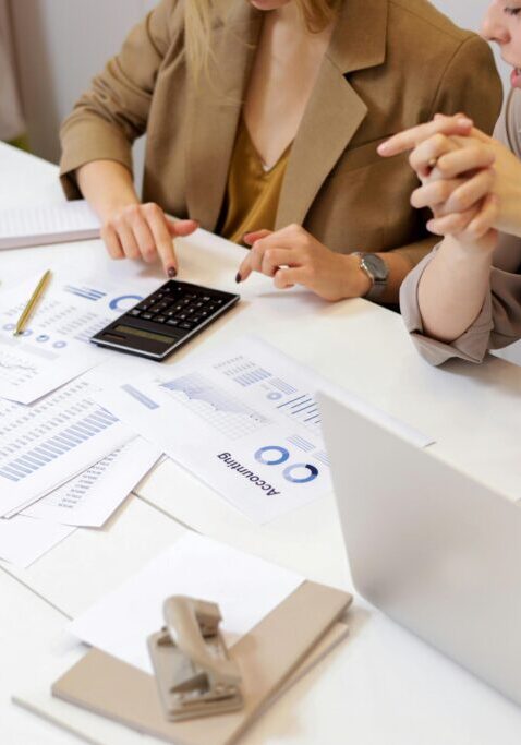 Two professionals reviewing documents and data at a desk.