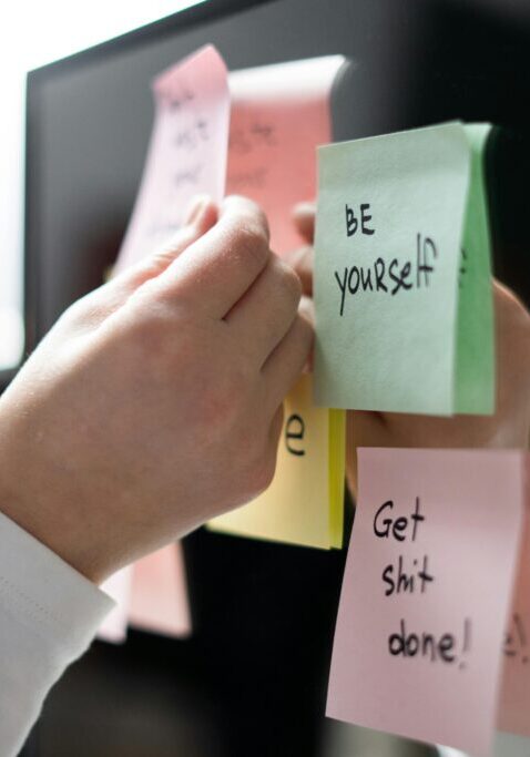 Sticky notes with motivational and self-critical messages on a computer.
