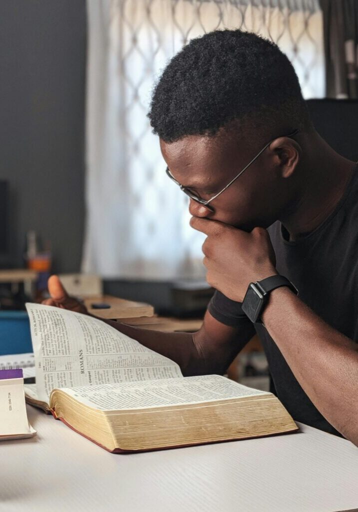 A man deeply reading a large book at a desk.