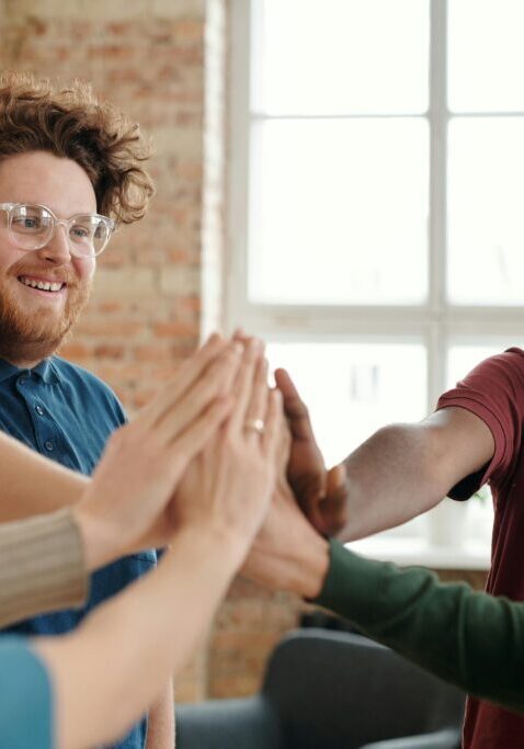 A group of diverse friends giving a group high-five indoors.