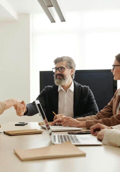 Business professionals shaking hands in a modern office meeting.