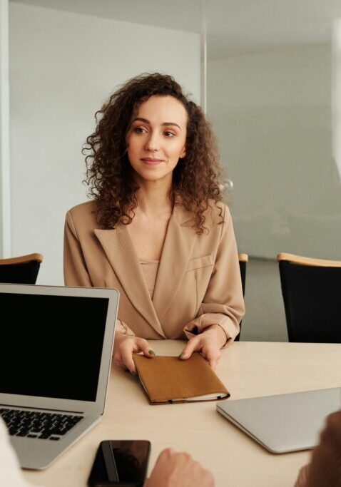 A woman in a business meeting with laptops and documents.