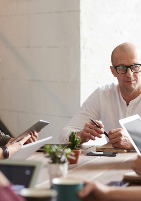 A group of professionals engaged in a meeting, discussing and using digital devices.