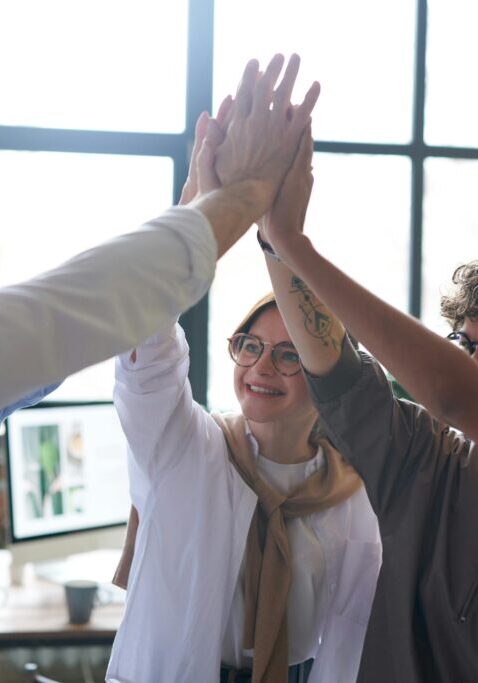 Group high-fiving in an office setting.