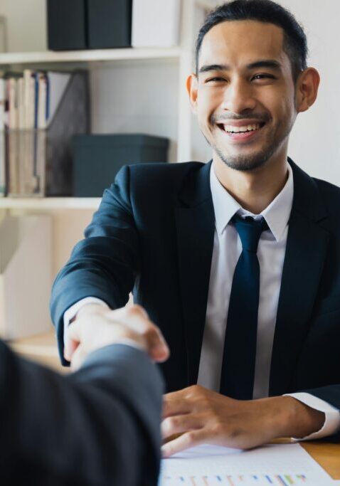 Young professional man shaking hands in a business meeting.
