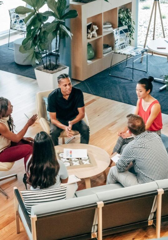 A group of five people having a discussion in a modern office lounge.