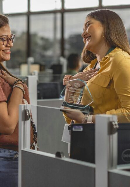 Two women enjoying a friendly conversation at an office workspace.