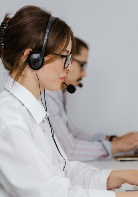 Two female customer support agents wearing headsets working on computers.