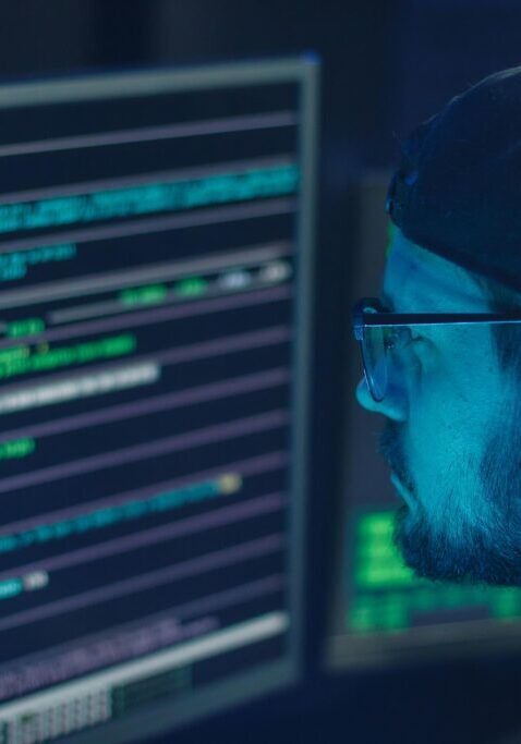 A man intently coding on a computer screen filled with lines of programming code.