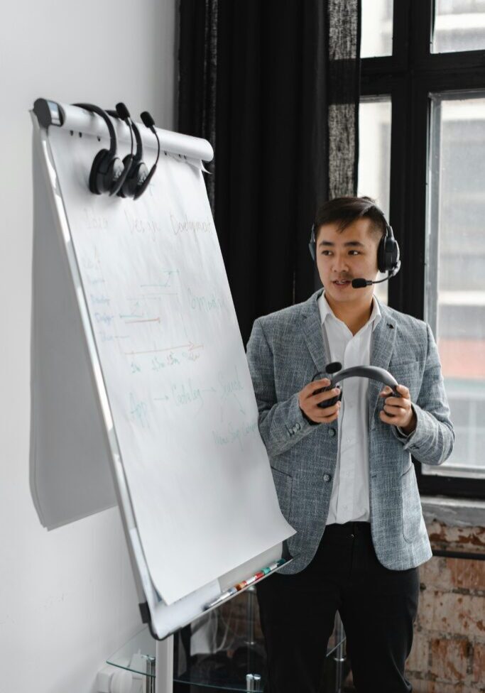 Man in a blazer giving a presentation with a headset and coffee mug.
