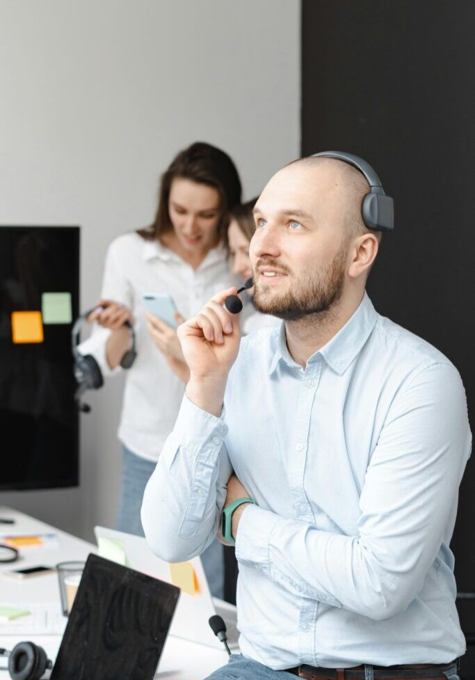 Man with headset thinking thoughtfully in an office.
