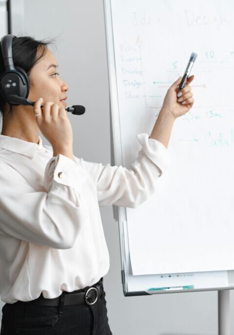 A businesswoman wearing a headset presenting with a whiteboard.