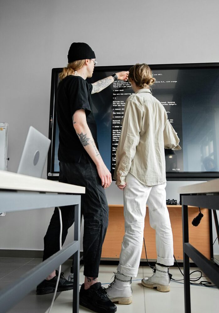 Two people collaborating in a modern office with digital screens.