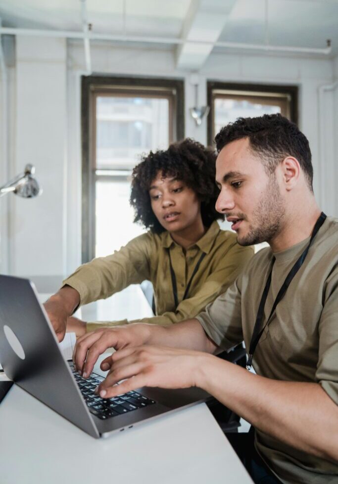Two colleagues collaborating on a laptop in an office.