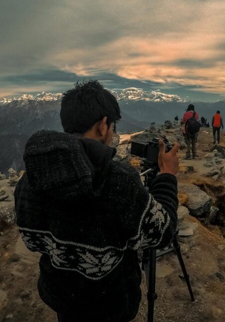 Photographer capturing a sunset from a mountain peak.