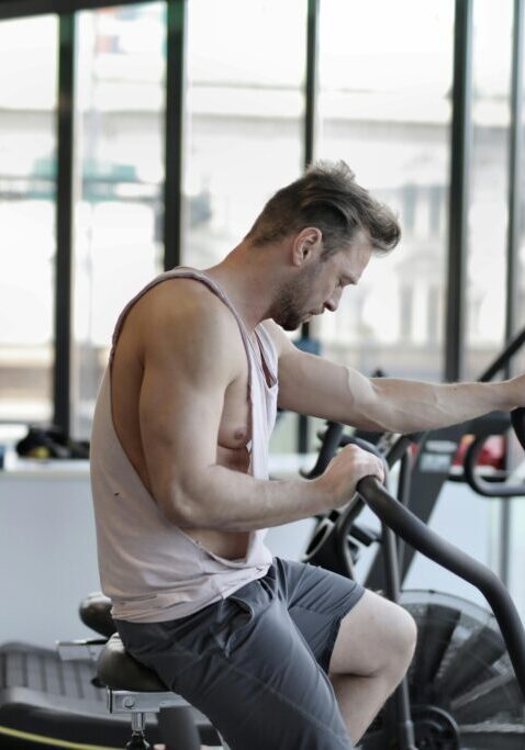 Man working out on a stationary bike in a gym.