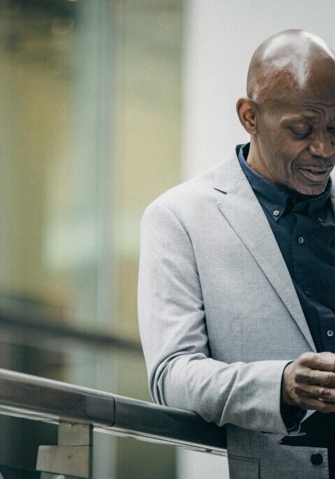 A man in a light gray blazer reads a document indoors.