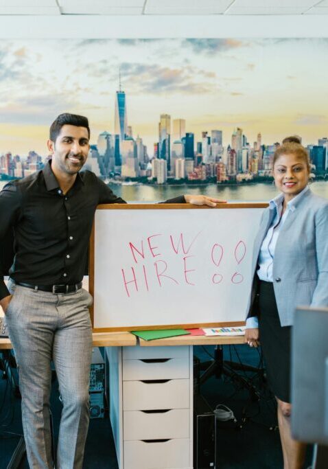 Four men posing confidently in an office with a cityscape backdrop and a whiteboard.