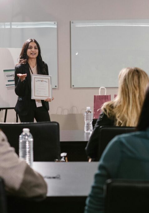A woman presenting a project to a small audience in a conference room.
