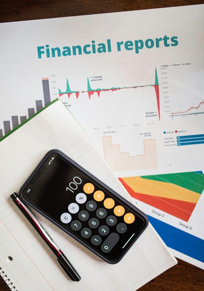 Calculator and phone on financial reports with charts and graphs.