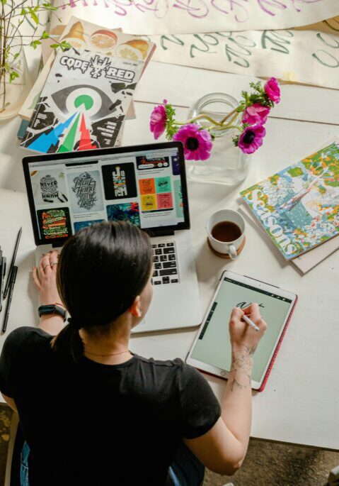 Person working on art and design projects at a cluttered desk.