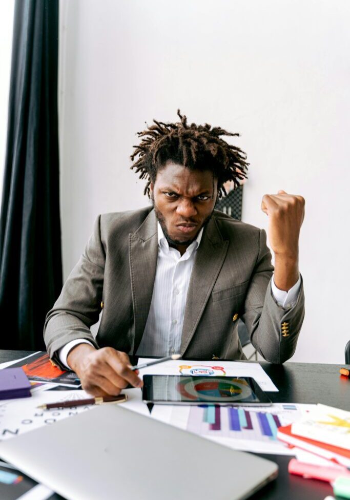 Man in suit celebrates success while working at desk.
