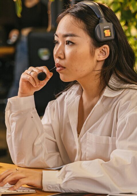Thoughtful woman sitting at a table, holding a pen and looking away.