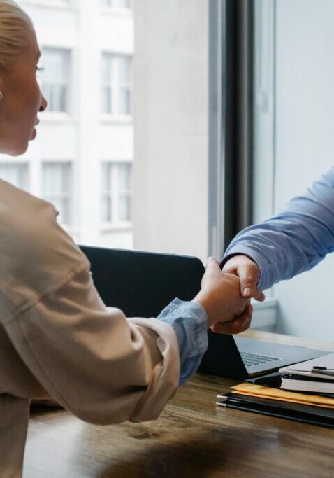 Two people shaking hands across desk