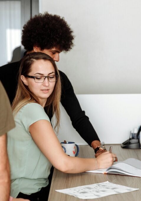 Two colleagues collaborating over documents in an office setting.
