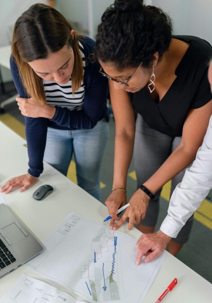 Two women collaborating and pointing at a document on a table.