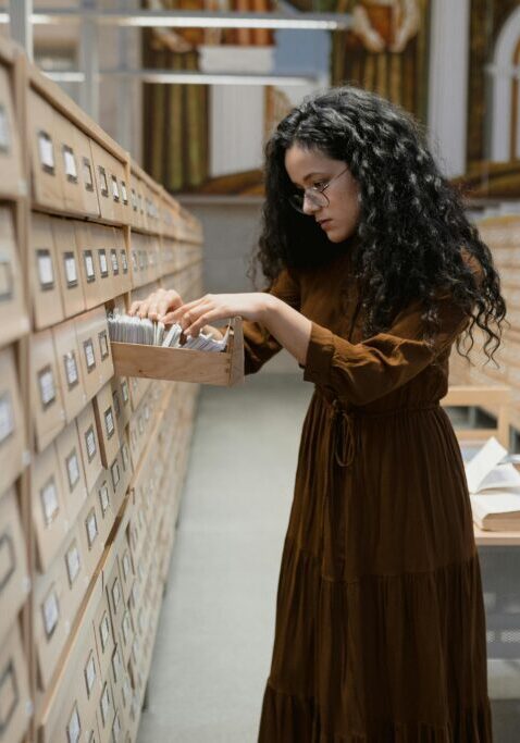 A woman searches through a card catalog in a library.