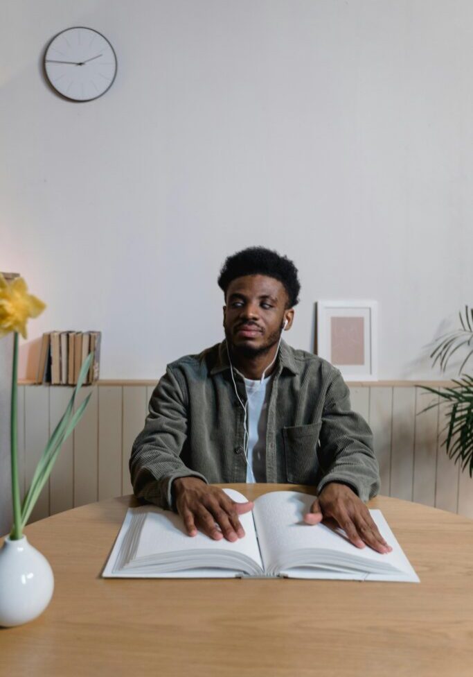 Young man sitting at a desk with an open book, smiling.